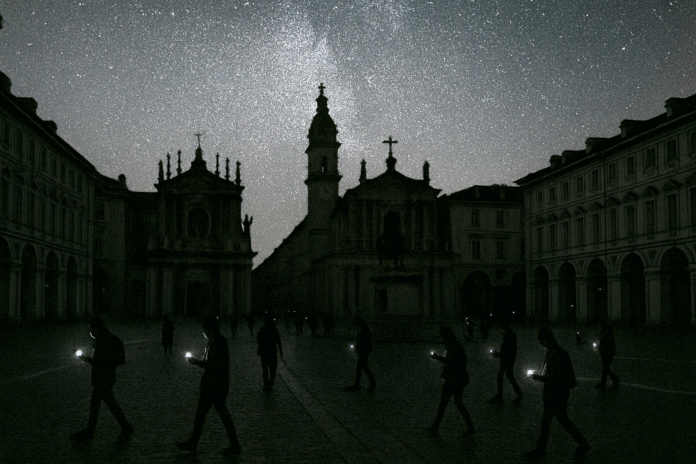 Una piazza di Torino completamente al buio durante il blackout, con persone che usano i cellulari per farsi luce.